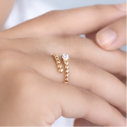 Gold ring with a diamond on a person's finger against a white background